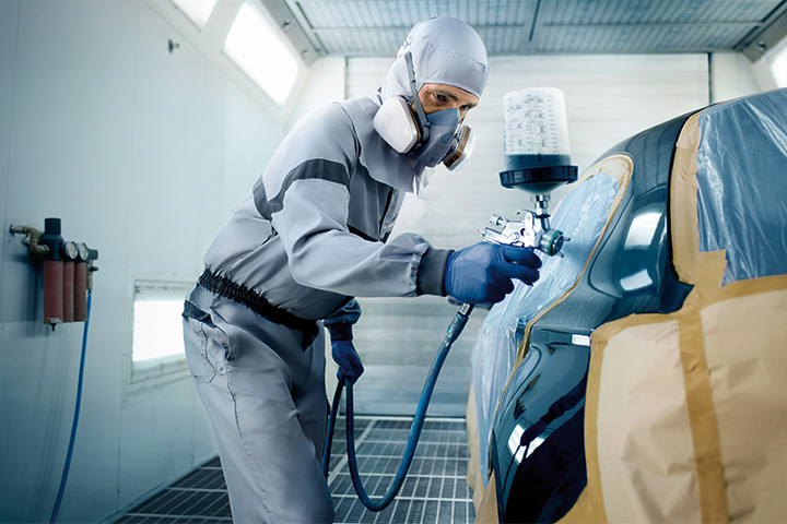 BMW trained painter wearing protective gear while performing paintwork on a BMW vehicle in a BMW spray booth. 