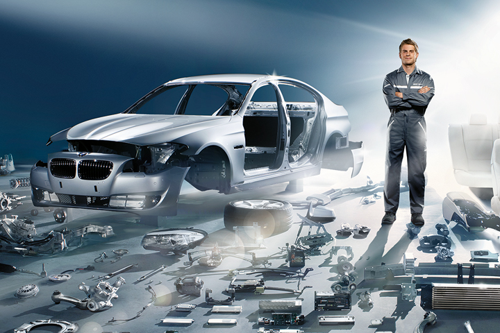BMW Service employee standing next to BMW parts.